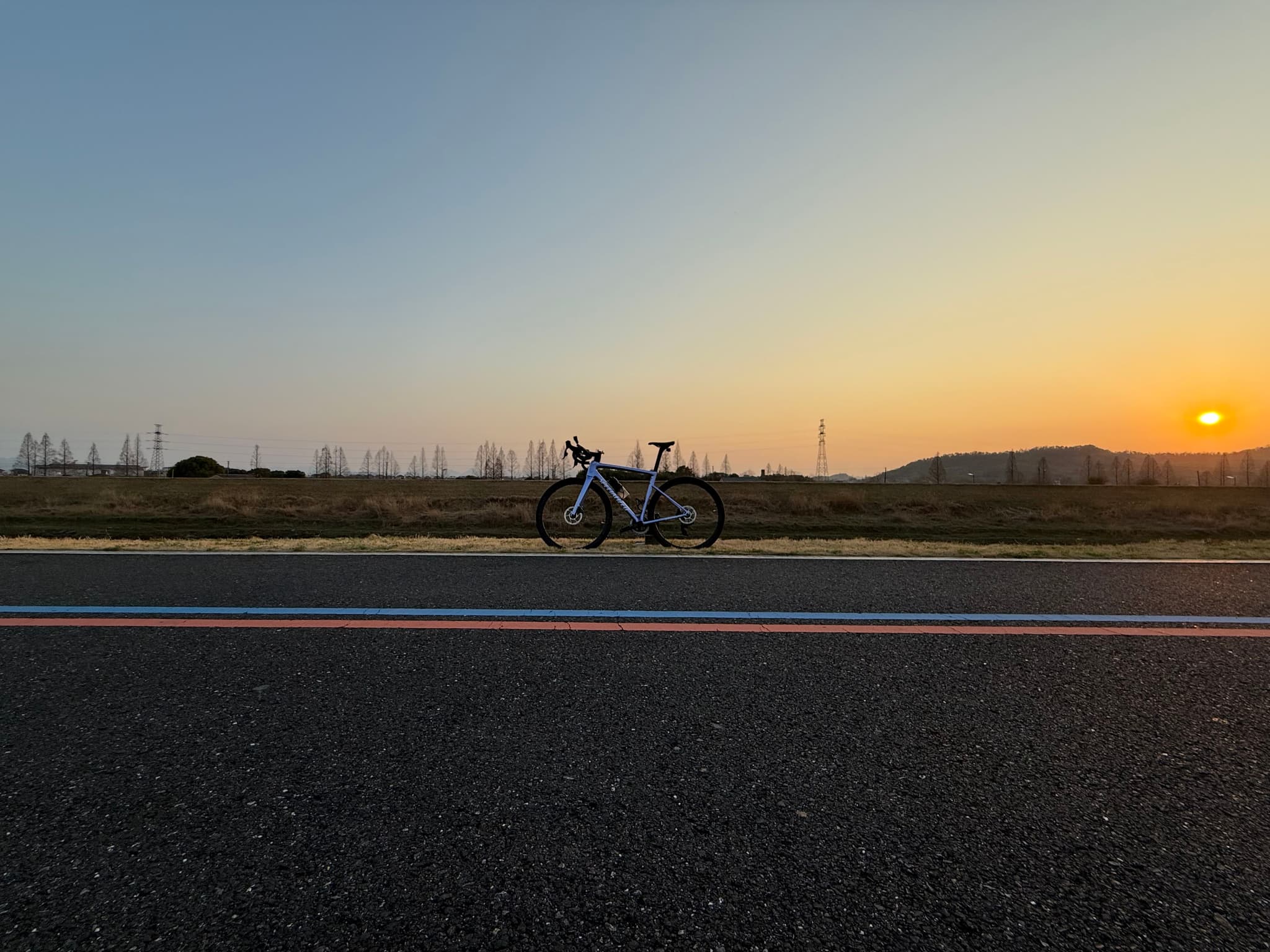 一辆自行车停在路边，背景是日落时分的天空和远处的地平线。