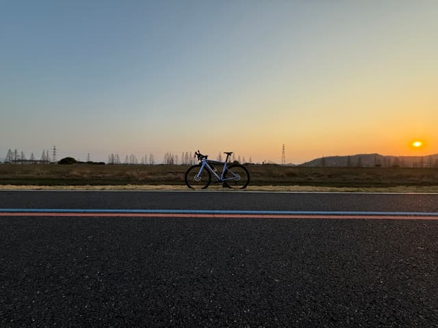一辆自行车停在路边，背景是日落时分的天空和远处的地平线。